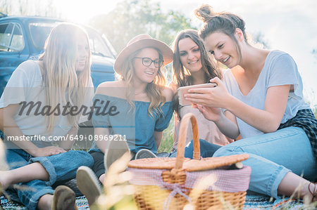Friends having picnic looking at smartphone smiling, Firenze, Toscana, Italy, Europe