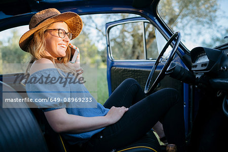 Woman in car using smartphone smiling, Firenze, Toscana, Italy, Europe