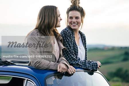 Tourists standing through car sunroof