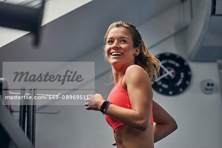 Young woman training, running on gym treadmill looking over her shoulder