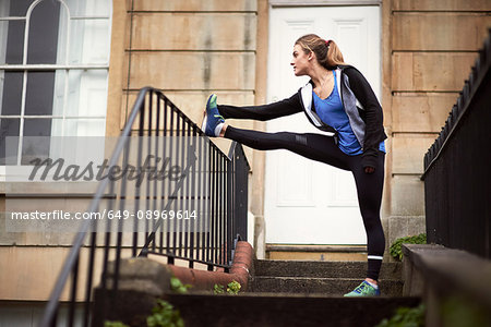 Young female runner outside front door touching toes