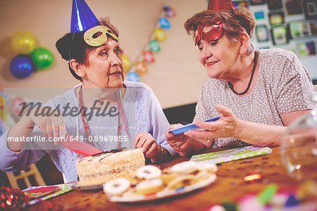Senior women serving birthday cake at party