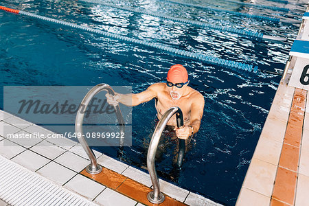 Senior man using ladder in swimming pool