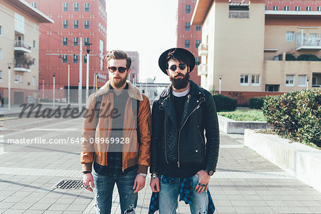 Portrait of two young male hipster friends standing in city housing estate