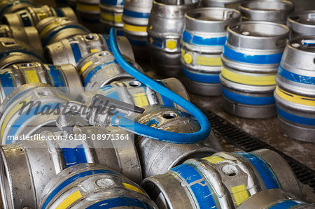 Close up of metal beer kegs being filled in a brewery.