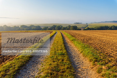 Countryside with dual track road path and morning mist in autumn in the village of Schmachtenberg in Bavaria, Germany Countryside with dual track road path and morning mist in autumn in the village of Schmachtenberg in Bavaria, Germany