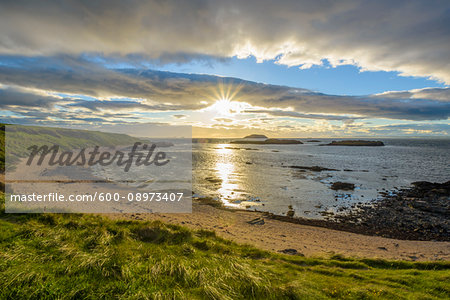 Sun shining over bay with sandy beach at sunset in North Berwick at Firth of Forth in Scotland, United Kingdom