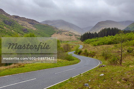 Winding country road and hills with overcast sky at Glen Nevis near Fort William in Scotland, United Kingdom
