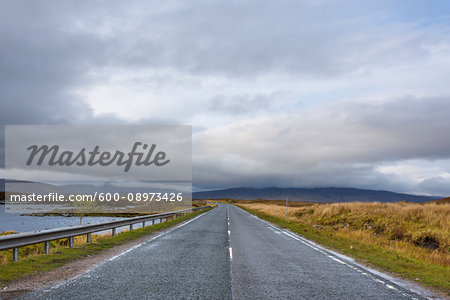 Country road through moor landscape with dense cloudy sky at Rannoch Moor in Scotland, United Kingdom