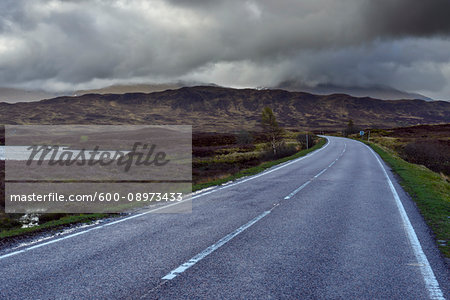 Country road through moor landscape with storm clouds at Rannoch Moor in Scotland, United Kingdom