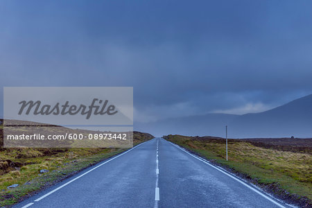 Country road with dark cloudy sky in the highlands on A82 road in Glen Coe, Scotland, United Kingdom