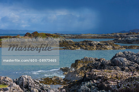 Scottish coast with rocky shoreline and storm clouds in the distance in spring at the port of Mallaig in Scotland, United Kingdom