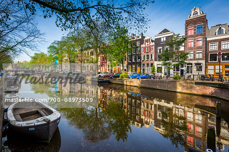 Boats and cars parked along the Herengracht Canal in the shade in Grachtengordel in Amsterdam, Holland