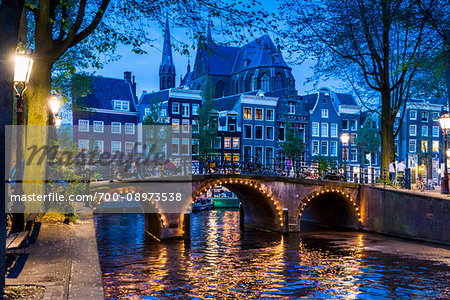 Stone bridge lit up at dusk along the Leidsegracht Canal in Amsterdam, Holland