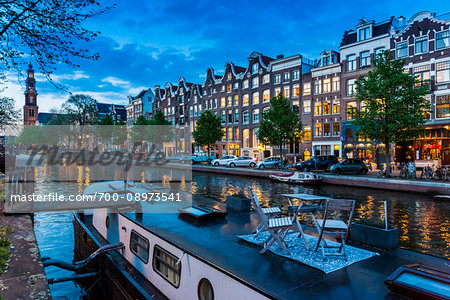 Table and chairs on top of a houseboat moored along the Prinsengracht canal at dusk in Amsterdam, Holland