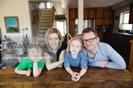 Portrait of parents at kitchen table with daughter and son