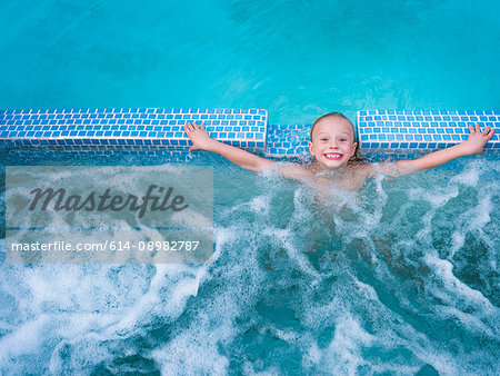 Overhead portrait of cute boy splashing in outdoor swimming pool
