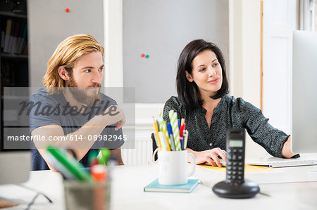 Female and male designers looking at computer in creative studio