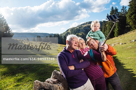 Three generation family in rural setting, taking selfie, using smartphone and selfie stick, Geneva, Switzerland, Europe