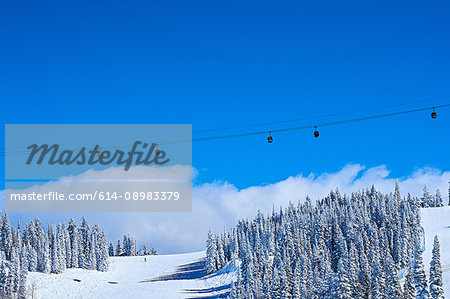 Cable car over snow covered mountains and blue sky, Aspen, Colorado, USA