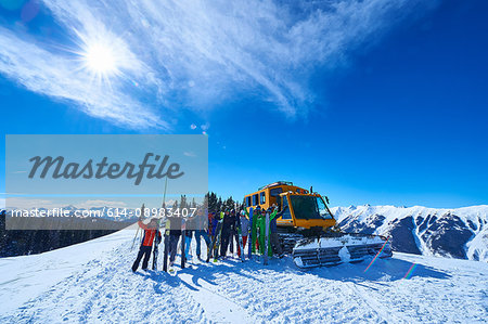 Group portrait of male and female skiers on ski slope by snow coach, Aspen, Colorado, USA