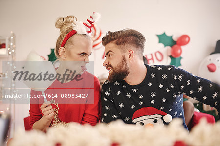 Young man and woman making faces at each other at christmas party