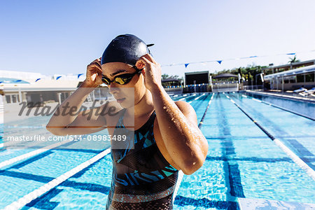Swimmer in swimming cap and goggles by pool