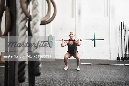 Woman lifting barbell in cross training gym