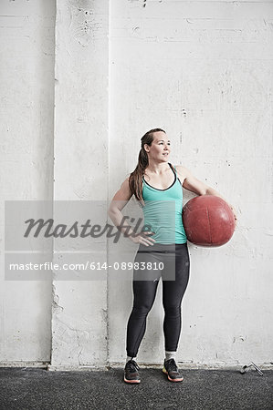 Woman carrying fitness ball in cross training gym