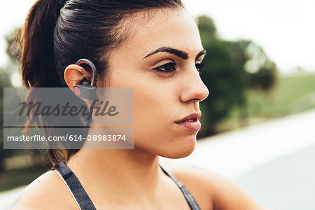Portrait of young woman outdoors, wearing earphones close-up, South Point Park, Miami Beach, Florida, USA