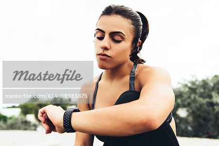 Young woman outdoors, checking activity tracker, South Point Park, Miami Beach, Florida, USA