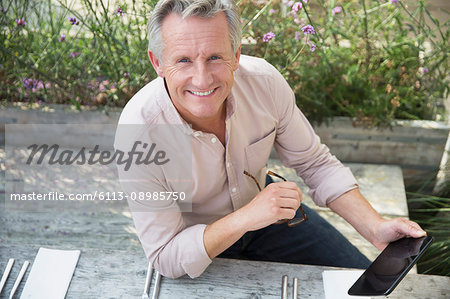 Portrait smiling senior man using digital tablet on patio
