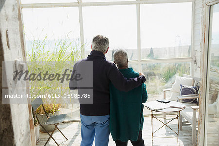 Affectionate senior couple enjoying beach view on sun porch