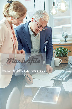 Business people planning, reviewing paperwork at digital tablet in meeting