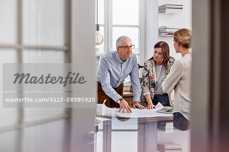 Architects reviewing, discussing blueprints in conference room meeting