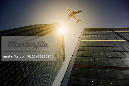 Airplane flying over highrise buildings, travel concept