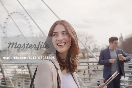 Smiling woman walking on urban bridge near Millennium Wheel, London, UK