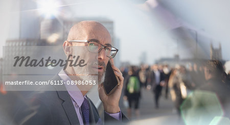 Serious businessman talking on cell phone on busy urban street