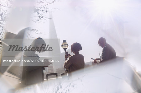 Business people using cell phones in sunny city, London, UK