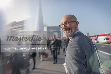 Portrait smiling businessman walking on busy urban sidewalk, London, UK