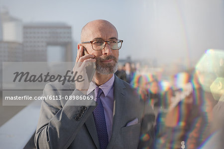 Businessman talking on cell phone on busy, urban pedestrian bridge
