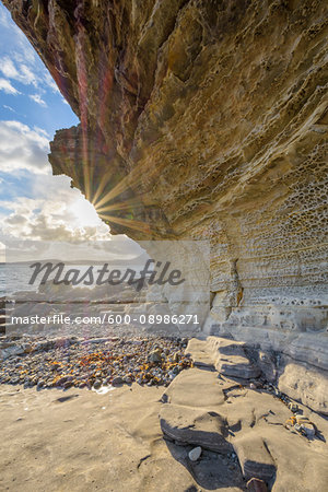 Close-up of rock face of sea cliff with honeycomb weathering and sun shining over Loch Scavaig on the Isle of Skye in Scotland, United Kingdom