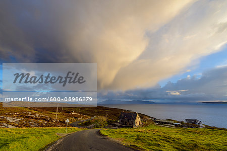 Road leading to the harbor with houses on the hillside and storm clouds over Loch Scavaig on the Isle of Skye in Scotland, United Kingdom Road leading to the harbor with houses on the hillside and storm clouds over Loch Scavaig on the Isle of Skye in Scotland, United Kingdom