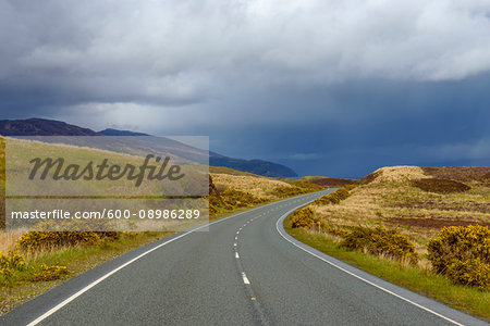 Winding country road with rainclouds in springtime on the Isle of Skye in Scotland, United Kingdom