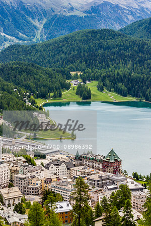 Overview of hotels and chalets on the shoreline of Lake St Moritz in the resrot town of St Moritz surrounded by the Swiss Alps on a sunny day in spring, Switzerland