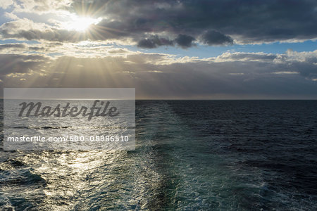 Ship's wake with sun shining through the clouds over the North Sea, United Kingdom