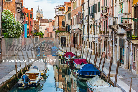 View of boats moored along a canal lined with historical buildings in Venice, Italy View of boats moored along a canal lined with historical buildings in Venice, Italy