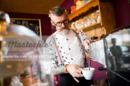 Quirky vintage senior man preparing coffee behind cafe counter