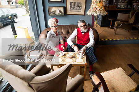 Quirky vintage couple having tea in tea room