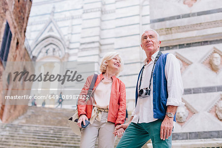 Tourist couple with camera and smartphone by city stairway, Siena, Tuscany, Italy